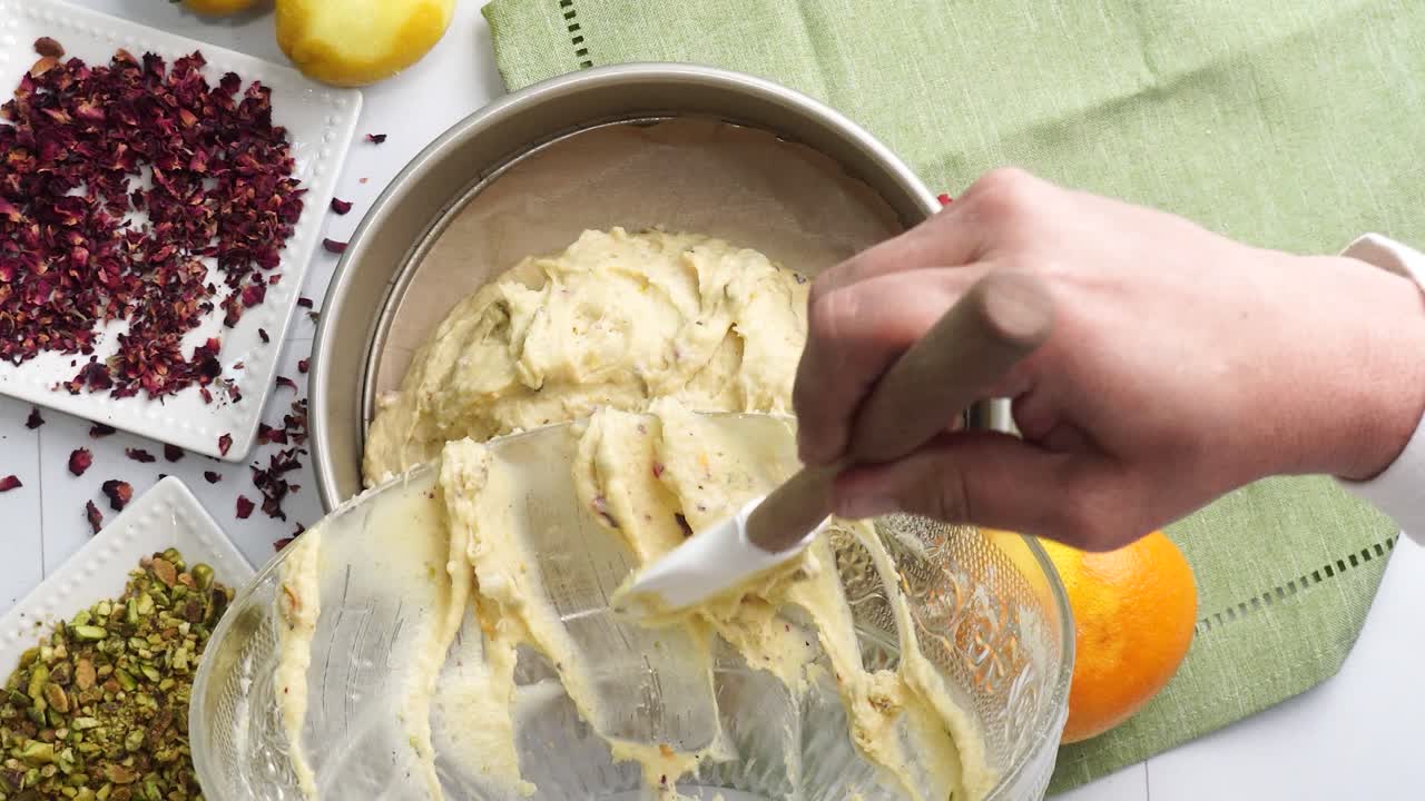 Baking a dessert called Persian Love Cake made with rose petals and pistachios. Cake with white glaze frosting. Adding cake batter to a springform pan. Beautiful cake for tea time or celebration