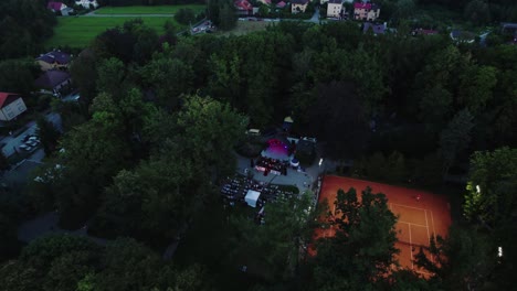 4k drone view of music stage and the crowd in public park at evening