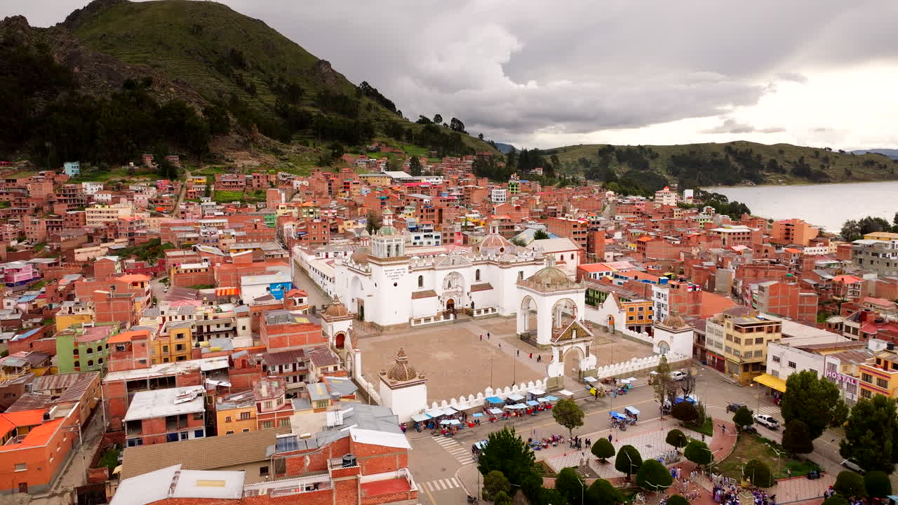 Vista aerea da drone della Basilica di Nostra Signora di Copacabana, circondata dalla città lacustre di Copacabana sul Lago Titicaca, in Bolivia, con colline andine, architettura storica e piazza cittadina visibili