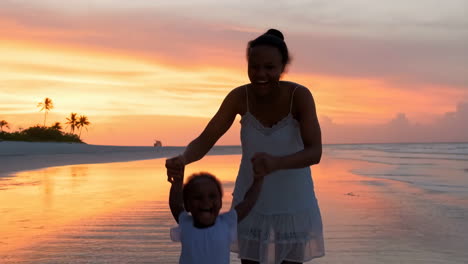 mother and child playing on a tropical beach at sunset