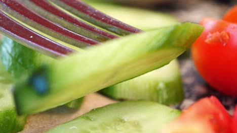 cerca de un tenedor recogiendo una rodaja de pepino de una ensalada