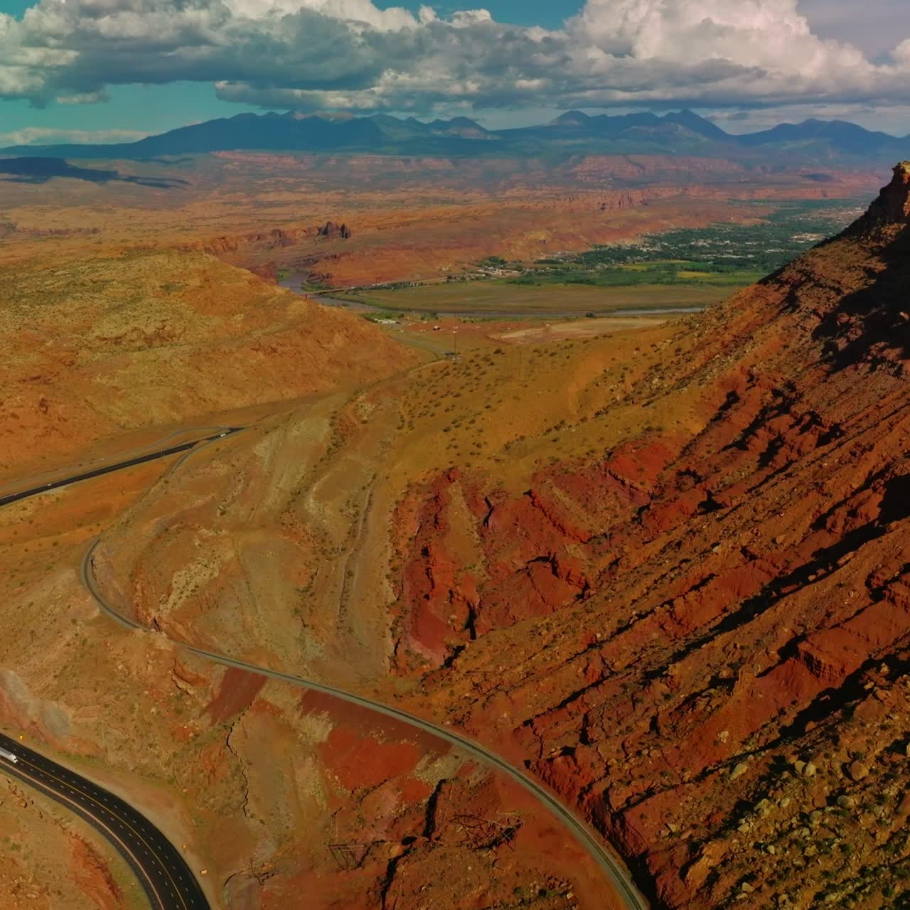 Rocky scenery of amazing canyons in Utah, USA. Motorway leading to the green valley. Stunning cloudscape at backdrop