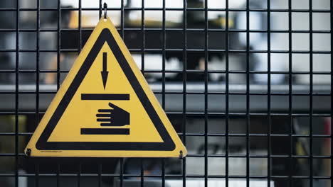 Yellow-factory-safety-sign-on-grid-at-industrial-plant-machine-background