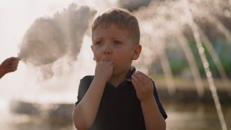 Emotional-little-boy-puts-hands-with-candy-floss-into-mouth