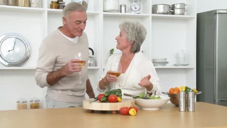 smiling senior couple preparing a salad in the kitchen