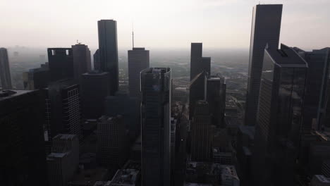 flying in middle of buildings in downtown houston, hazy day in texas, usa - aerial view