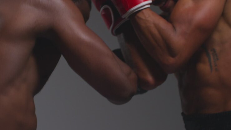 Close Up Studio Shot Of Two Male Boxers Wearing Gloves Fighting In Boxing Match Against Grey Background 14