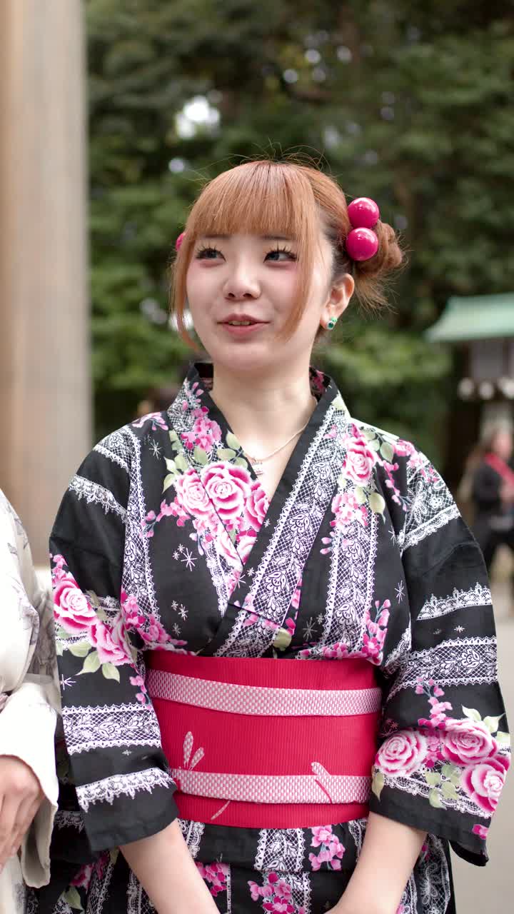 Una giovane donna giapponese che indossa un tradizionale yukata floreale si trova all'esterno di un santuario storico.
