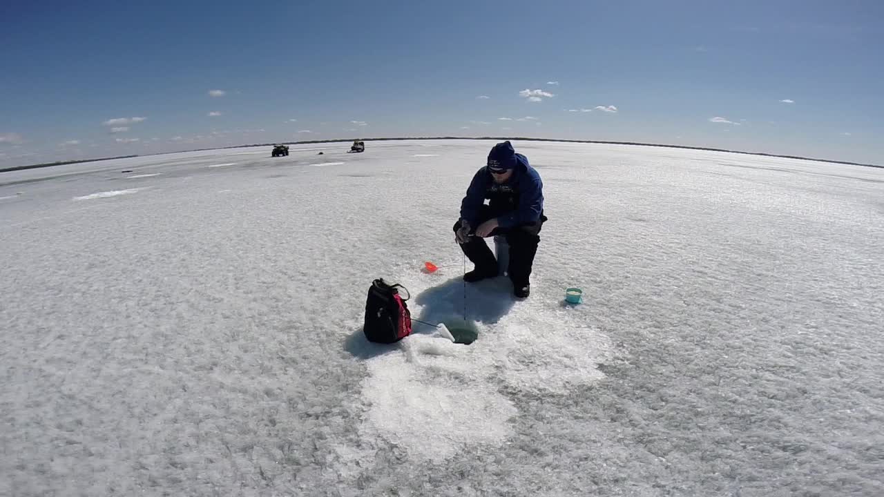Person Ice Fishing on a Frozen Lake