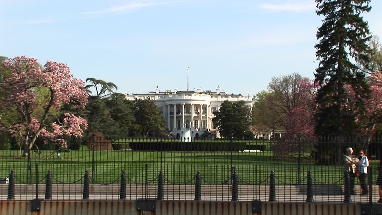 la cámara se acerca para ver más de cerca la casa blanca y la bandera estadounidense que ondea en lo alto