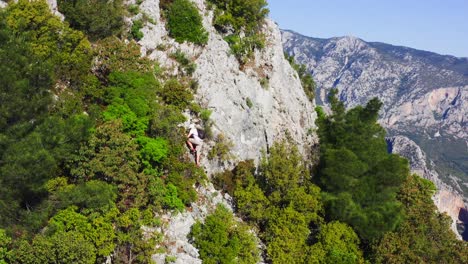 vista desde un avión no tripulado en la ladera empinada de la montaña con un hombre escalando las rocas entre la vegetación de garrigue , península de datça, turquía