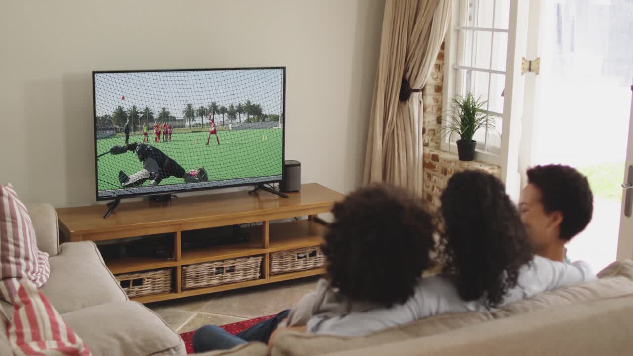 Famiglia felice seduta a casa insieme che guarda una partita di hockey in TV