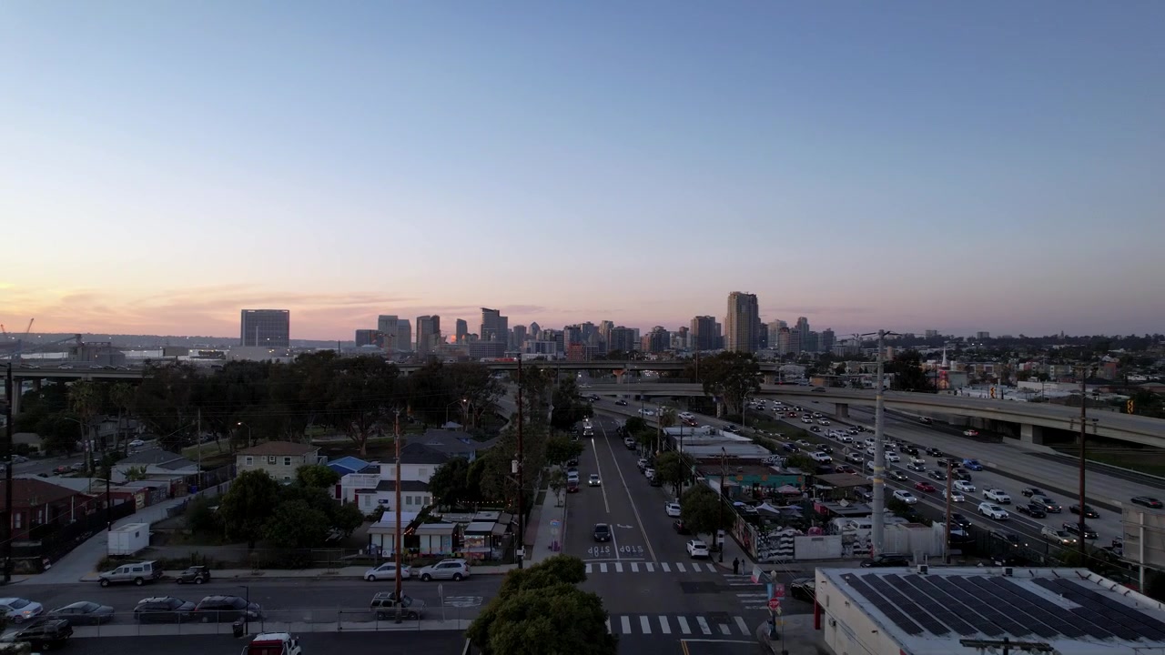 Drone in volo verso lo skyline del centro di San Diego al tramonto, da bassa quota, che cattura un'ampia veduta cinematografica della città.