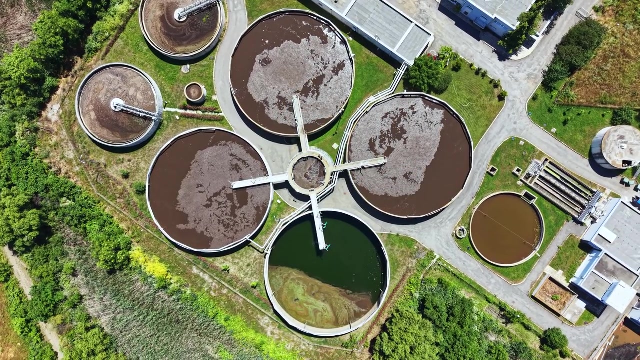 Una planta de tratamiento de agua, ubicada en una zona natural, opera grandes tanques para procesar aguas residuales y mantener los estándares ambientales.