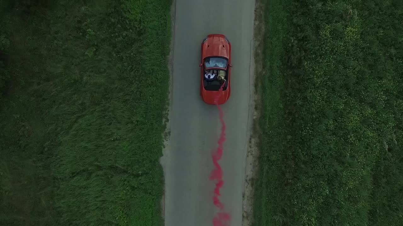 coche descapotable rojo conduciendo en una carretera de campo