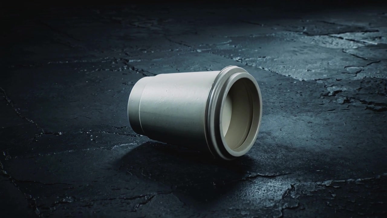 Camera capturing pale cylindrical container rotating on cracked floor, light revealing inner rim