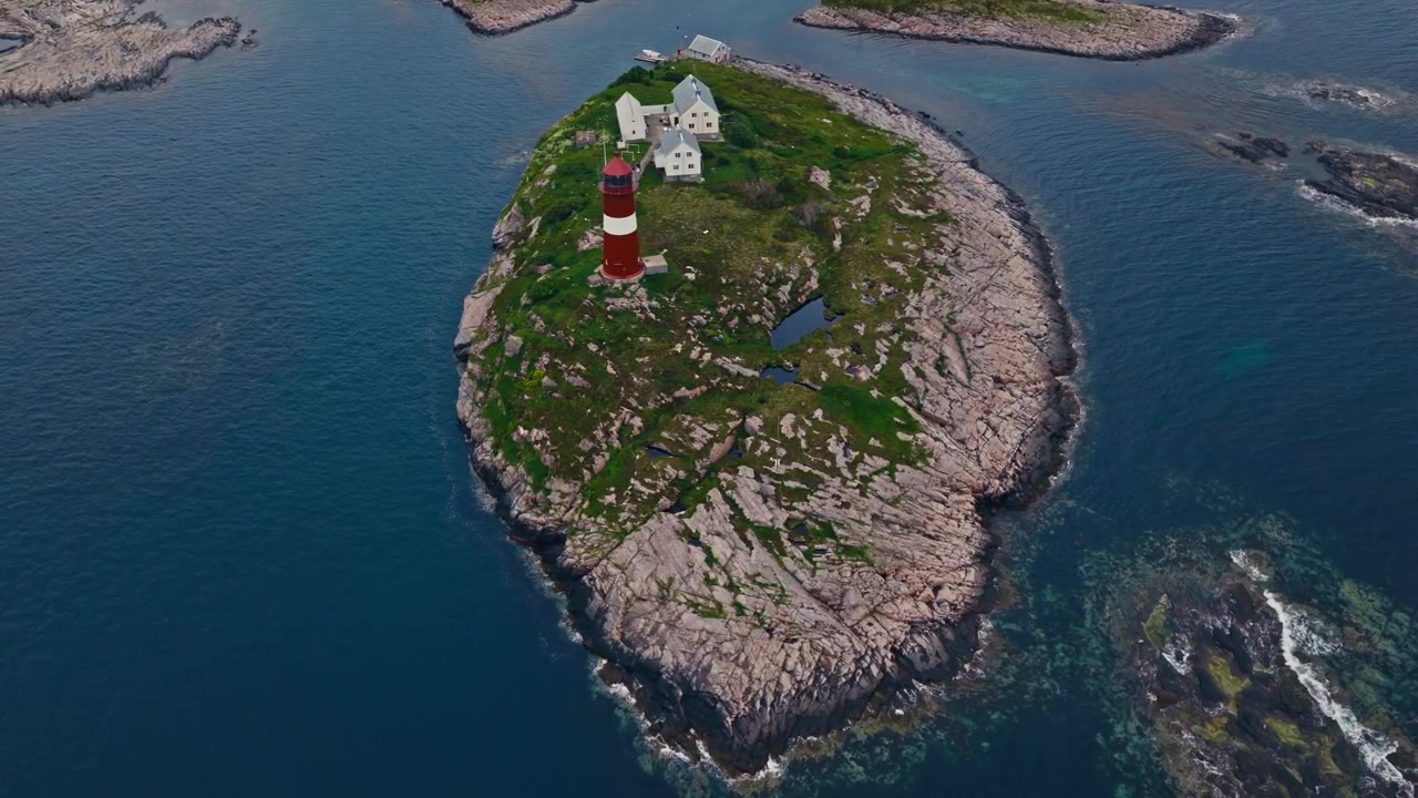 Faro di Buholmråsa, Comune di Osen, Trøndelag, Norvegia - Una vista aerea del faro rosso e bianco e degli edifici vicini su un'isola rocciosa circondata da acque costiere di un blu profondo