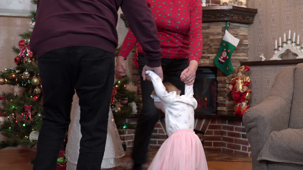 크리스마스를 맞아 손을 잡고 춤을 추는 가족 - 할아버지, 할머니, 손녀가 새해를 축하합니다.