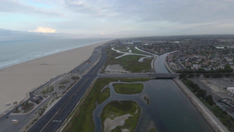 a drone flies high above the beach coast revealing ocean front luxury homes in orange county