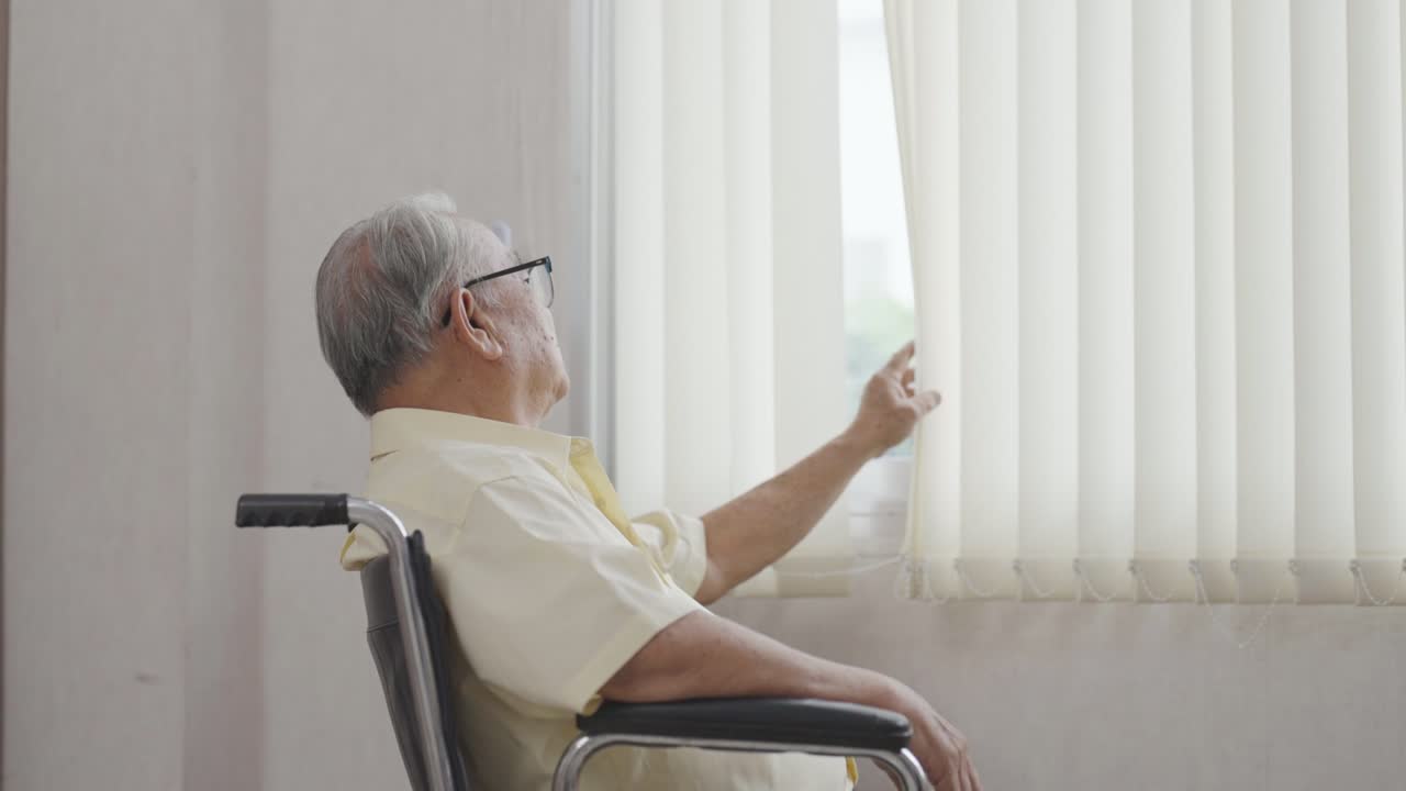 은 아시안 남자가 체어에 앉아 창밖을 바라보고 있습니다.