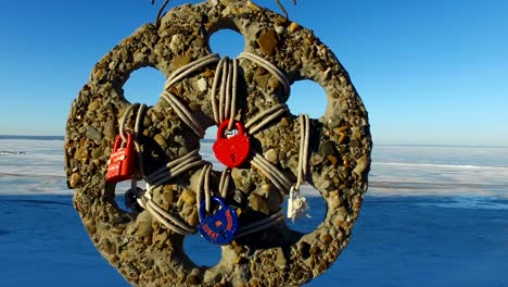 great wedding amulet hanging on the crossbar. he swings from strong winds. several locks are attached to the amulet. winter sunny cold day.