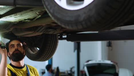 repairman inspects car on overhead lift