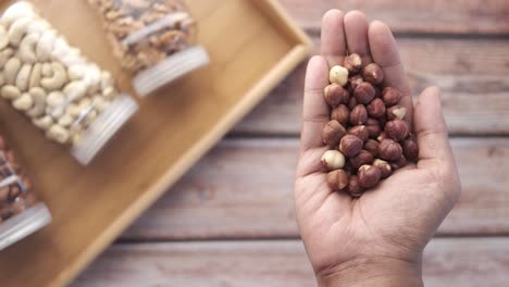 Handful of Hazelnuts with Other Nuts in Jars