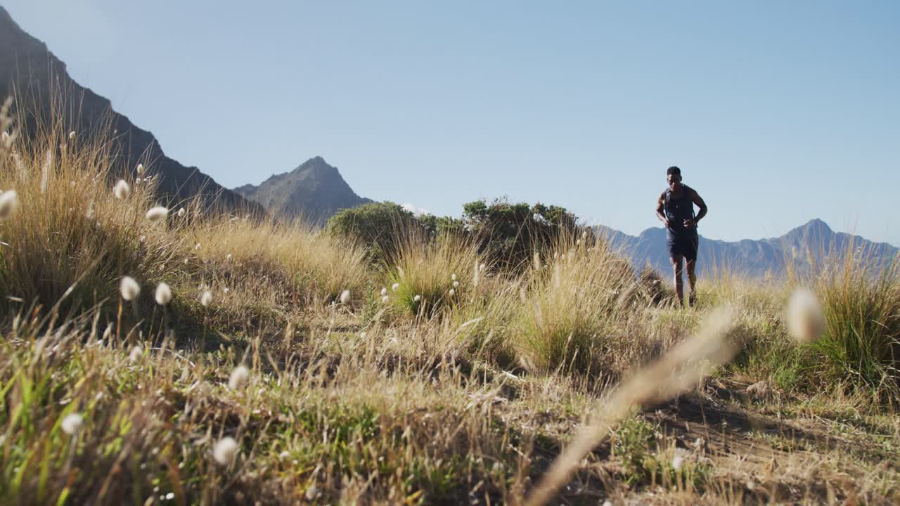 hombre afroamericano haciendo ejercicio al aire libre a través del país corriendo en el campo por la costa