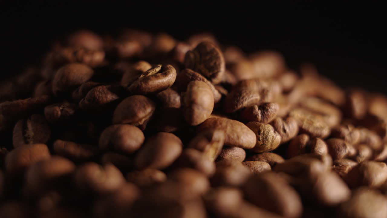 Statische Aufnahme mit Fokusverlagerung über einem Haufen Kaffeebohnen.