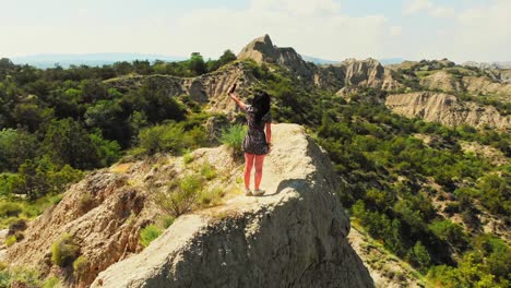 drone disparó a una joven caucásica de pie en la cima de la montaña. turista usando teléfono inteligente para hacerse una selfie juntos en el punto de vista. disparo aéreo, naturaleza, concepto de viaje y aventura.