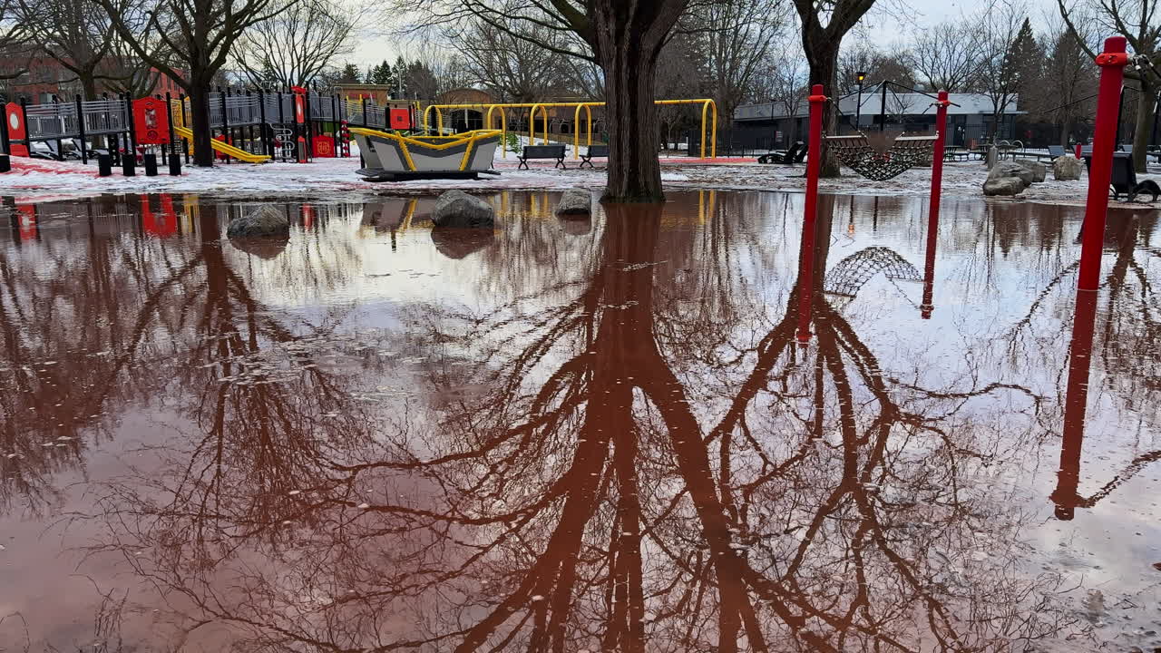 Sudden spring snowmelt floods a public playground, leaving the play area unusable as winter breaks apart and fast meltwater takes over the park