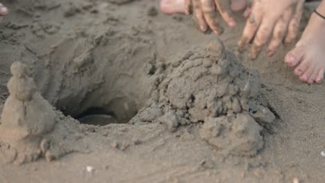 close up shot of a child who wants to build a sandcastle with the sand on the beach during summer vacation and is having fun on the trip together with her parents in slow motion