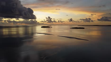 Aerial-view-of-islands-in-tropical-lagoon-at-sunset-with-golden-sky-and-clouds