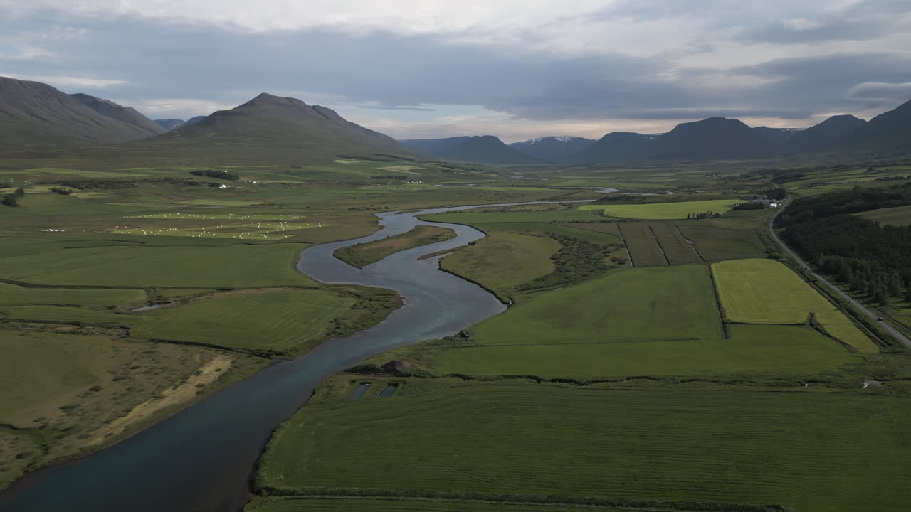 Aerial tracking left over river flowing through Akureyri Valley countryside, Iceland