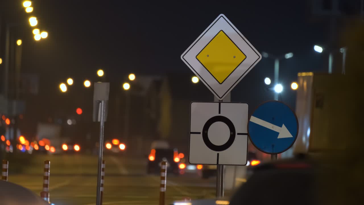 señales de carretera de rotonda con coches borrosos en el tráfico callejero de la ciudad por la noche. concepto de transporte urbano
