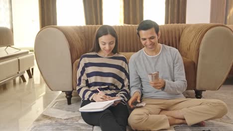 happy and rich indian couple counting money and doing future planning