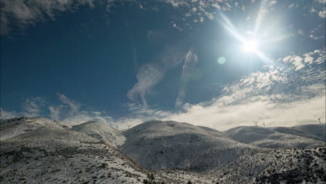 timelapse, nubes y sol brillante sobre montañas nevadas al pie de la colina