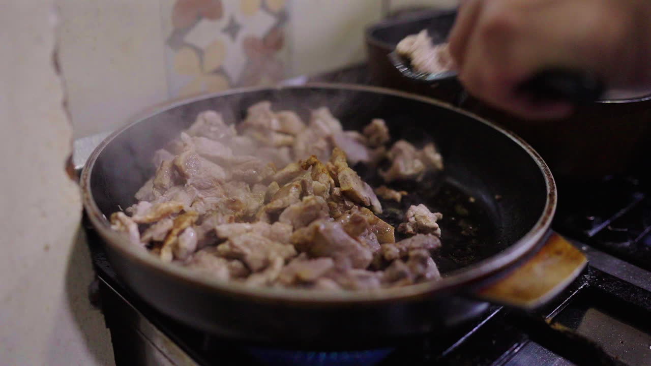 Sliced pork cooking in pan, steam rising, rustic kitchen, Italian dish Bagna Cauda