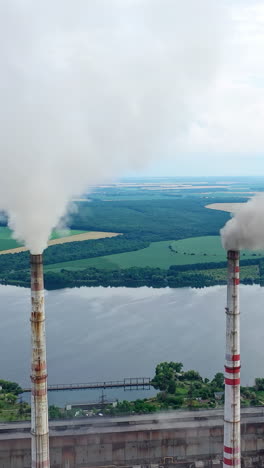 white stack of smoke coming out from large chimneys. factory chimneys releases harmful emissions into the atmosphere on nature backdrop.environmental problems. vertical video