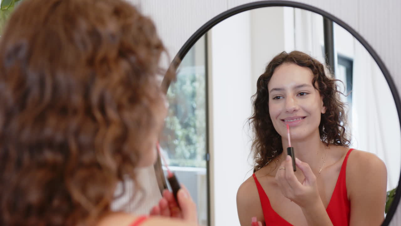 Applying lip gloss, woman looking in mirror, getting ready for day