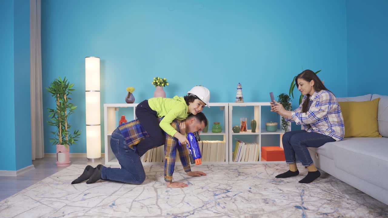 Mature father playing with his little son. The boy is riding on his father's back and playing cowboy.