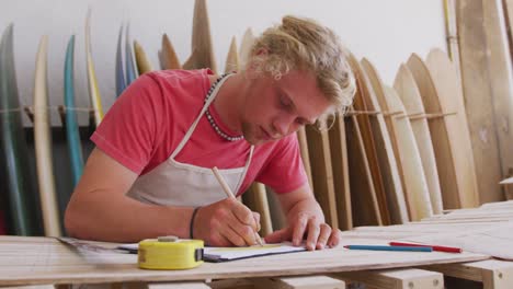 Caucasian-male-surfboard-maker-working-in-his-studio-and-making-a-wooden-surfboard