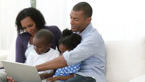 panorama de una familia afroamericana usando una computadora portátil en el sofá