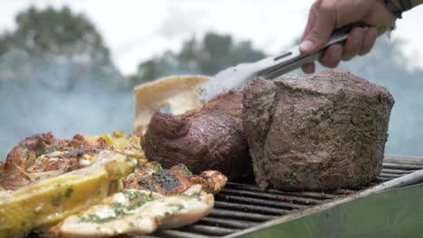 close shot of a man picking up the roasted meat with tong from the barbeque