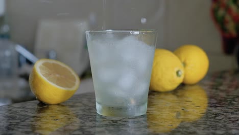 Limonade-Mit-Eiswürfeln,-Die-In-Glas-Gegossen-Werden-Und-Die-Arbeitsplatte-Bespritzen