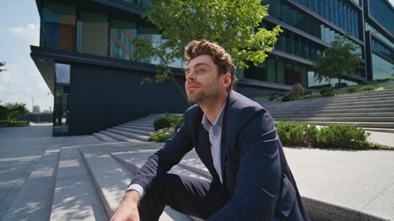 사려 깊은 매니저는 커피를 마시며 계단을 고 앉아있는 도시 지역을 즐기고 있습니다.