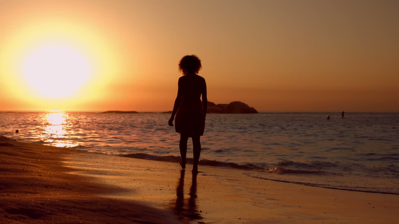 mujer caminando por la playa durante el atardecer