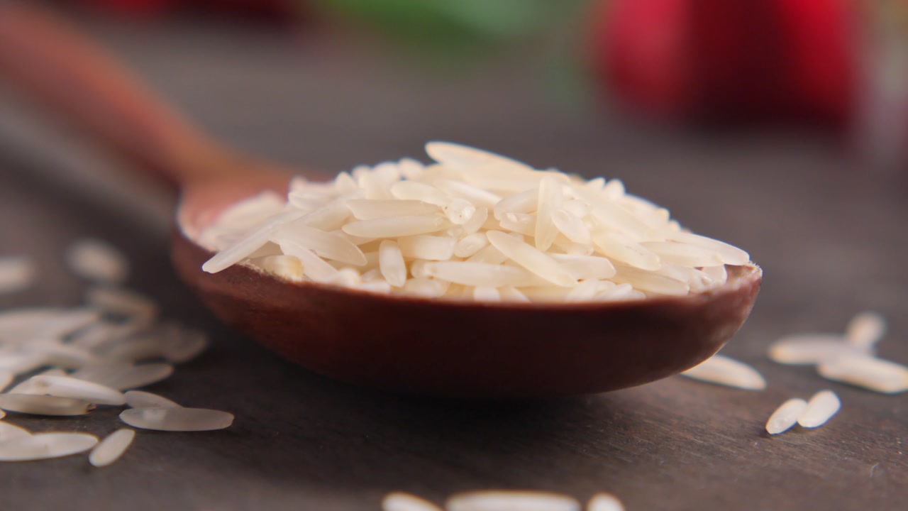 Raw Basmati Rice Grains in a Wooden Spoon on a Dark Table