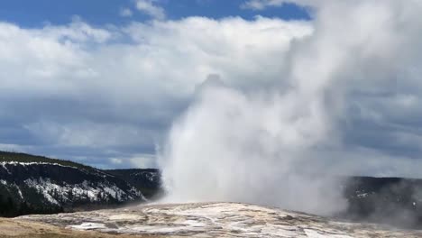 yellowstone national park old faithful geyser eruption on partially cloudy day