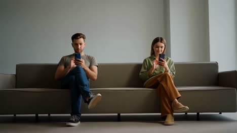 Two People Sitting on a Couch, Each Absorbed in Their Smartphones